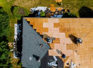 A large tree branch resting on a home’s shingled roof after a windstorm.