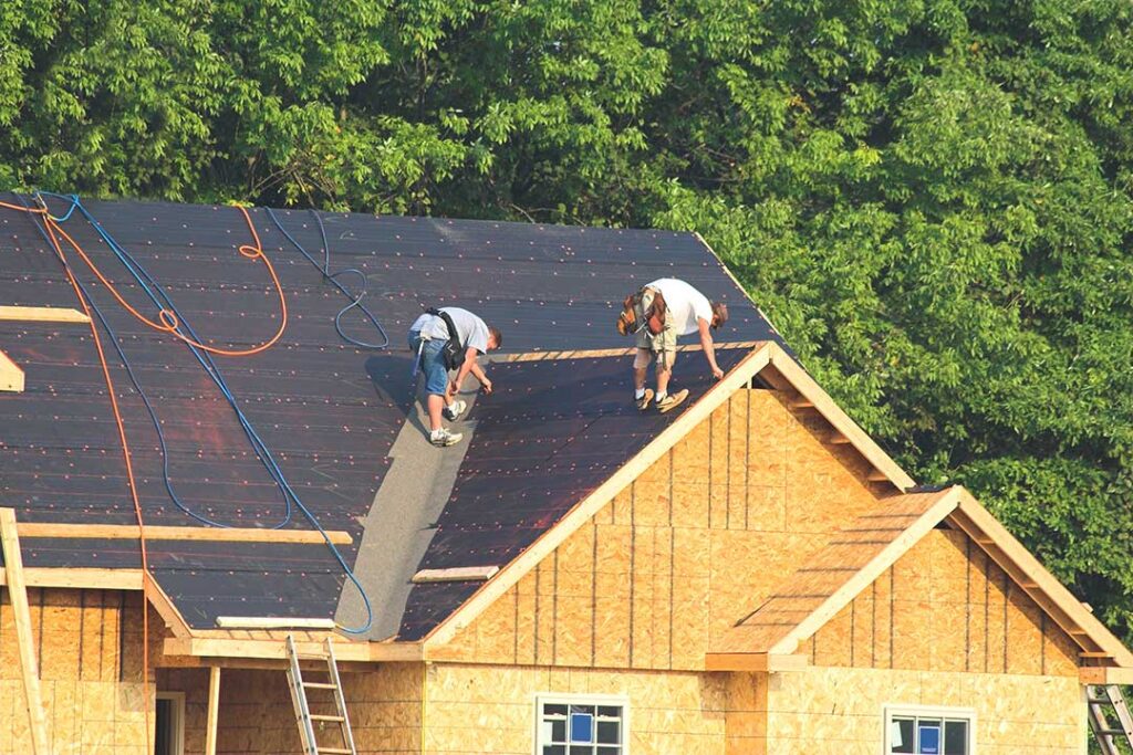 A homeowner compares a new asphalt shingle sample with weathered shingles on a residential roof.