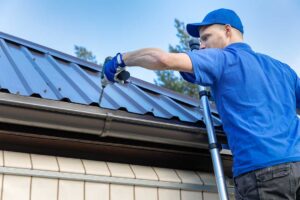 Homeowner examines roof shingles with binoculars while standing beside a house and inspecting the attic hatch.
