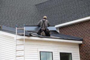 Inspector examining shingles and flashing on a residential roof after winter, with gutters and melting snow visible.