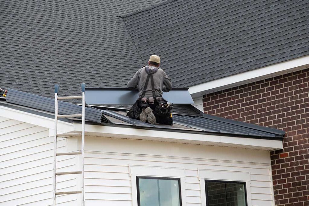 Snow-covered house roof with an ice ridge along the eaves and icicles hanging above a gutter.