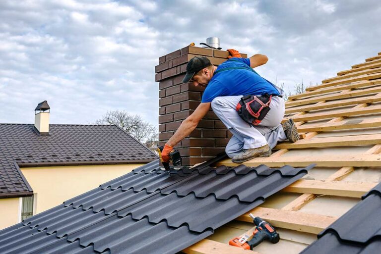Person placing dry holiday lights and wreaths into labeled storage bins on shelving in a clean attic.