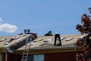A worker rolls a white protective coating across a clean low-slope roof beside roof drains and flashing.