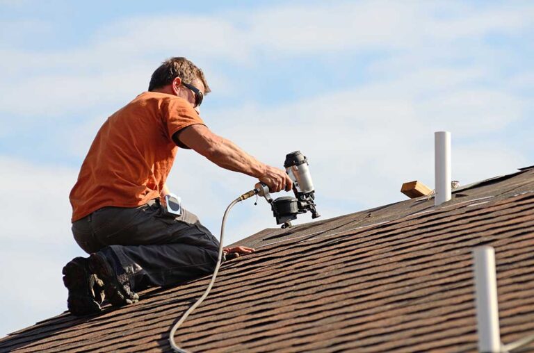 A peaked roof cricket behind a masonry chimney directs rainwater around both sides of the chimney.