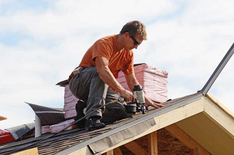 Homeowner examining roof shingles, flashing, gutters, and attic ventilation on a two-story house.
