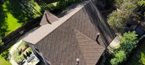 Homeowner reviewing roof components with a simple diagram beside shingles, flashing, gutters, and attic ventilation.
